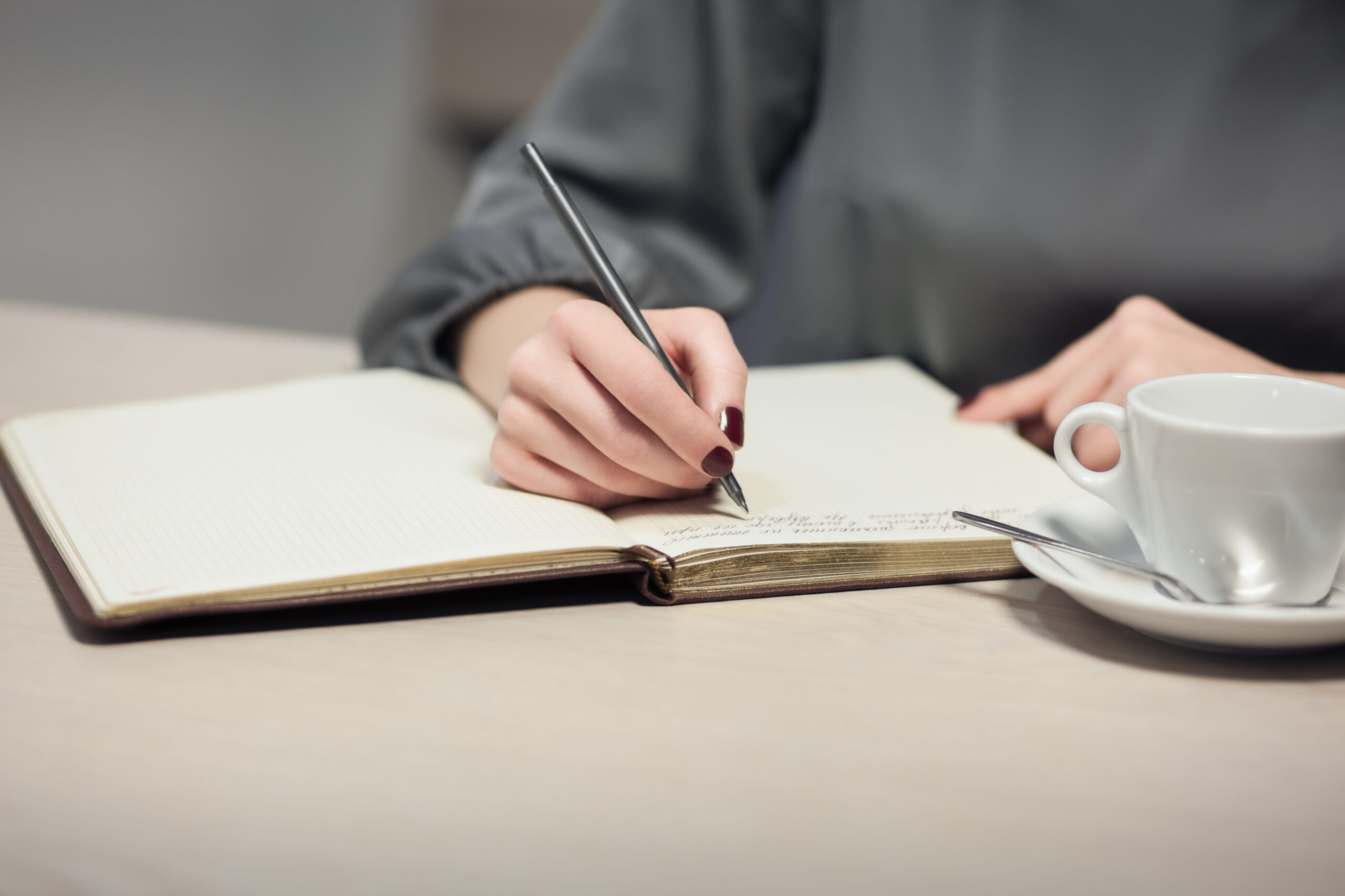 female has coffee break and writing notes in diary;